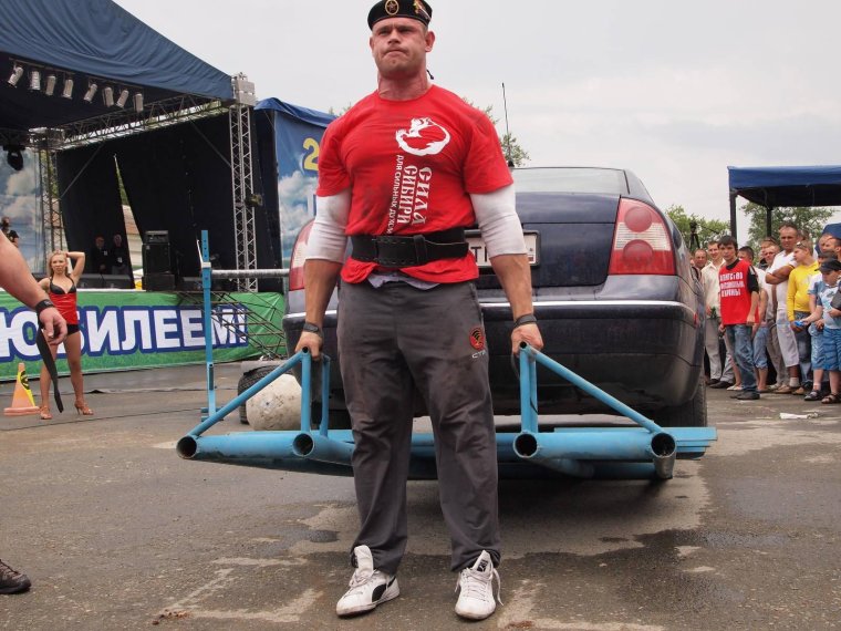 Силач поднимает автомобиль