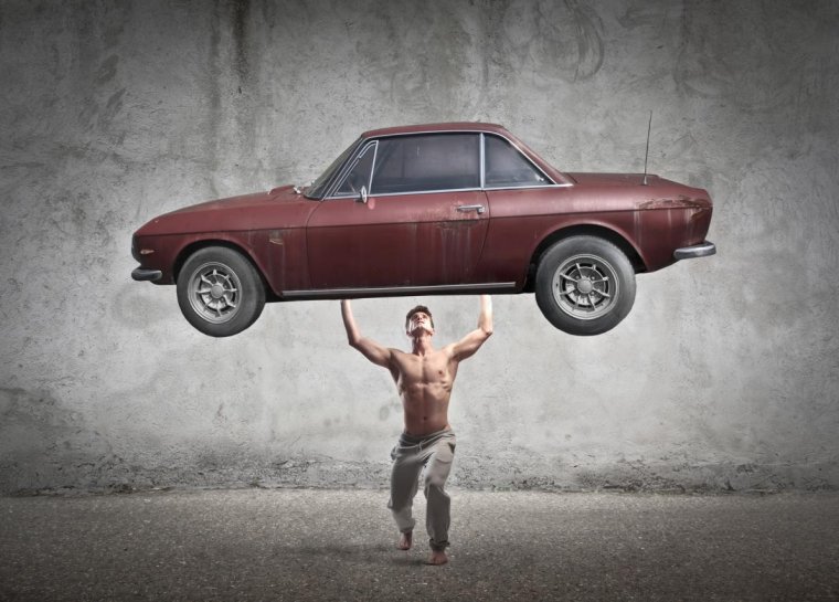 Человек поднимает машину