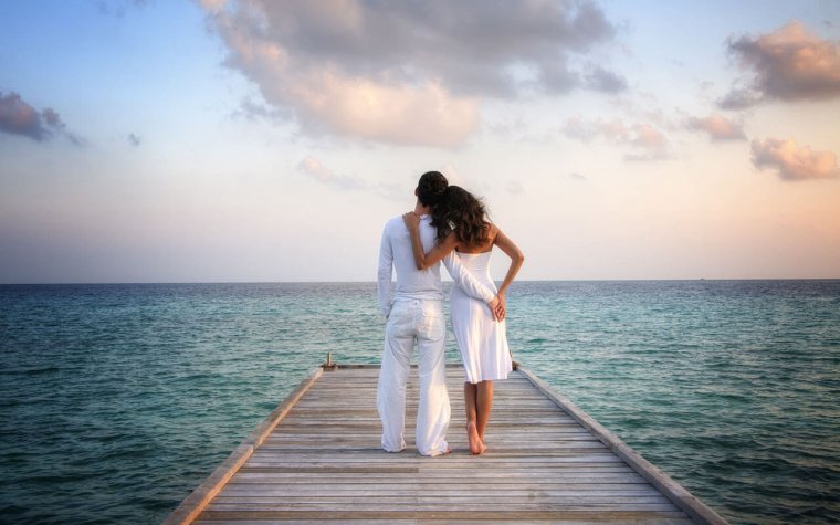 Влюблённая пара сидит на берегу