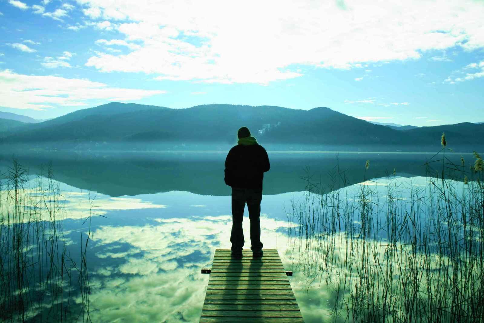 Далекий размышлять. Люди на озере. Одинокий человек на берегу. Уединение с природой. Человек у реки.