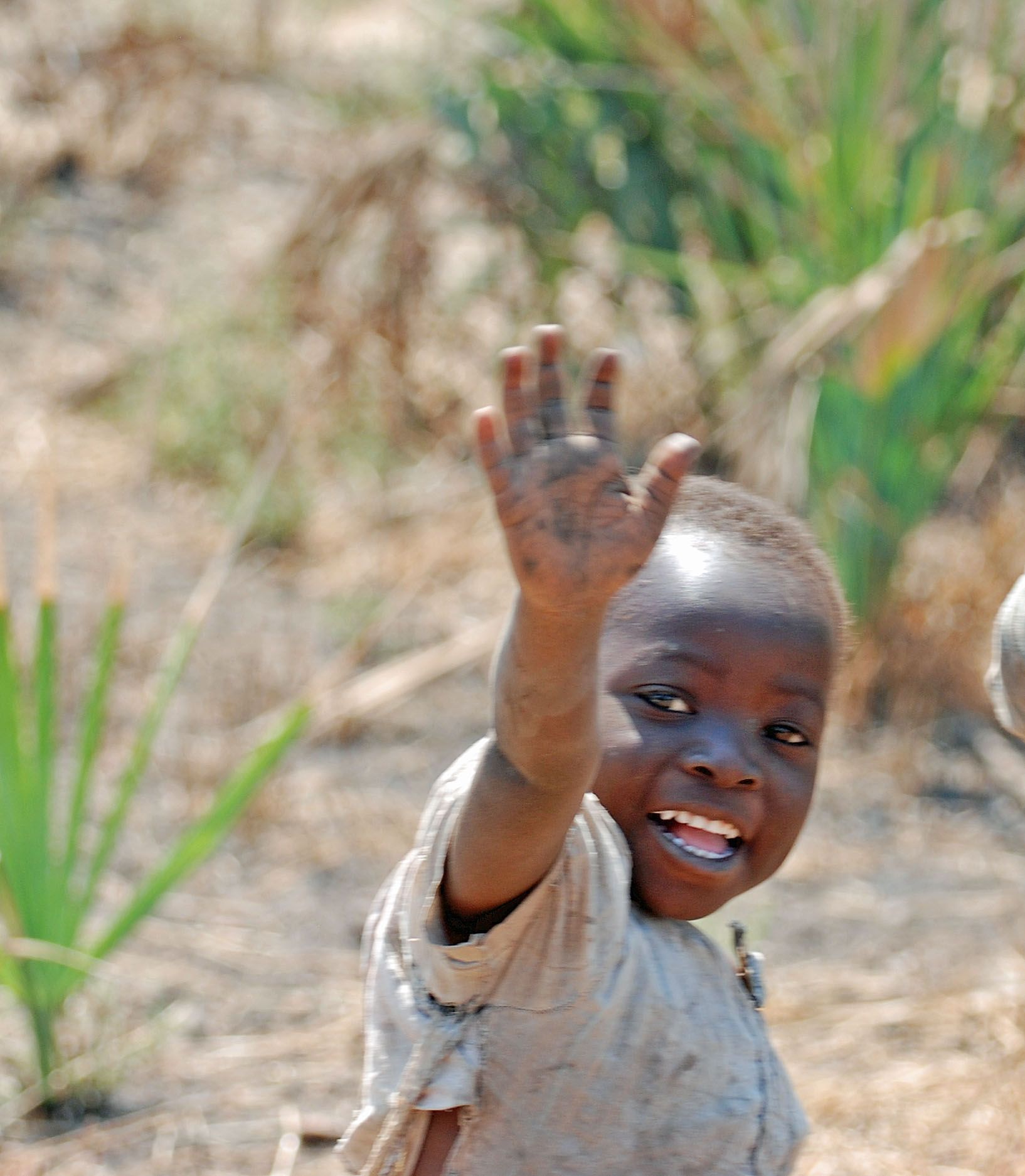 Чернокожий африканец. Счастливые дети Африки. Маленький негр. Африканец машет рукой.