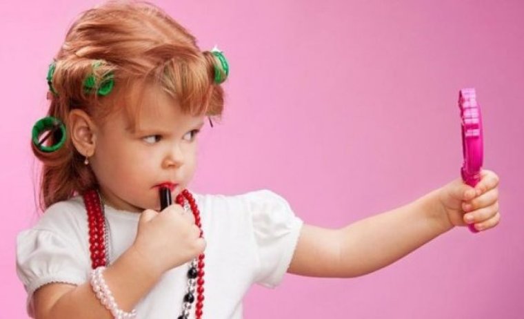 Маленькая девочка красит губы